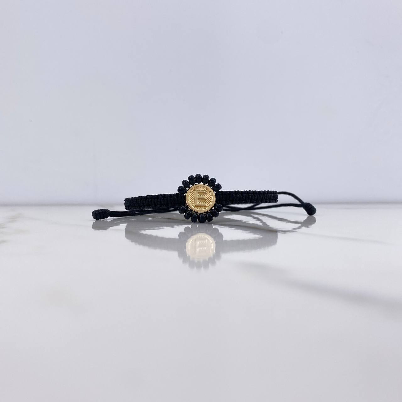 Pulsera Negra Herraje Letra E 0.55gr / 1cm / Tambor Mostacilla Checa Negra Oro Amarillo $